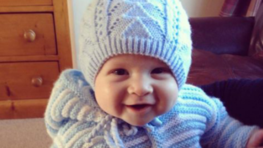 Smiling baby wearing a knitted blue hat.