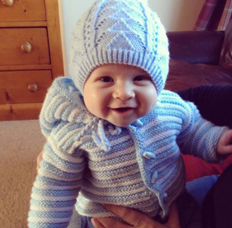 Smiling baby wearing a knitted blue hat.