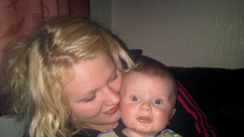 Mother holding her baby, with her head close to their head.