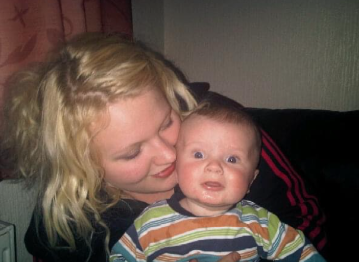 Mother holding her baby, with her head close to their head.