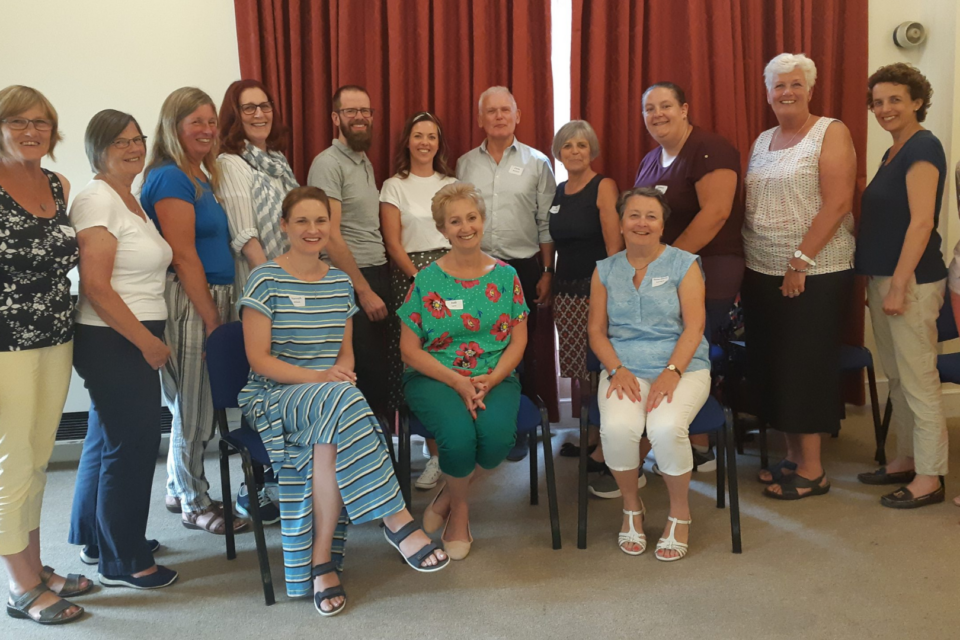 A group of volunteers together with two sitting in front of the group