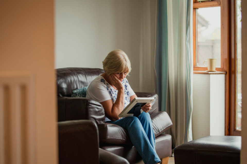 Woman is looking down at a photo. She has her hand on her chin.