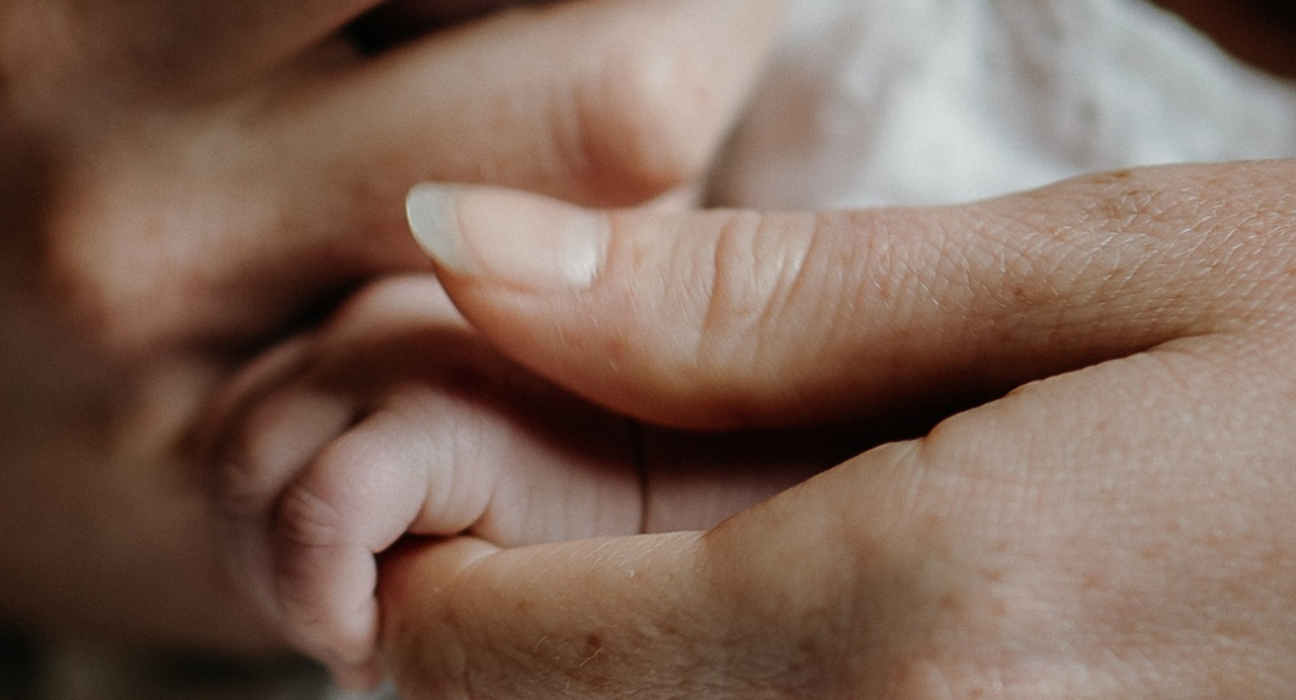 A close up of a baby's hand grasping the parent's hand