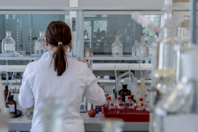 A researcher from the back, seemingly organising lab samples, wearing a lab coat with her hair tied back.