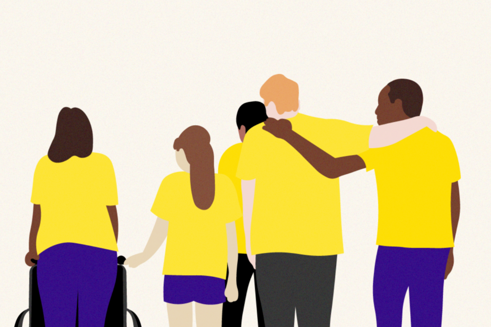 A group of people are supporting one another. They are different ages and from different backgrounds. One is pushing a wheel chair, and another has an arm around another person. It has a supportive feel.