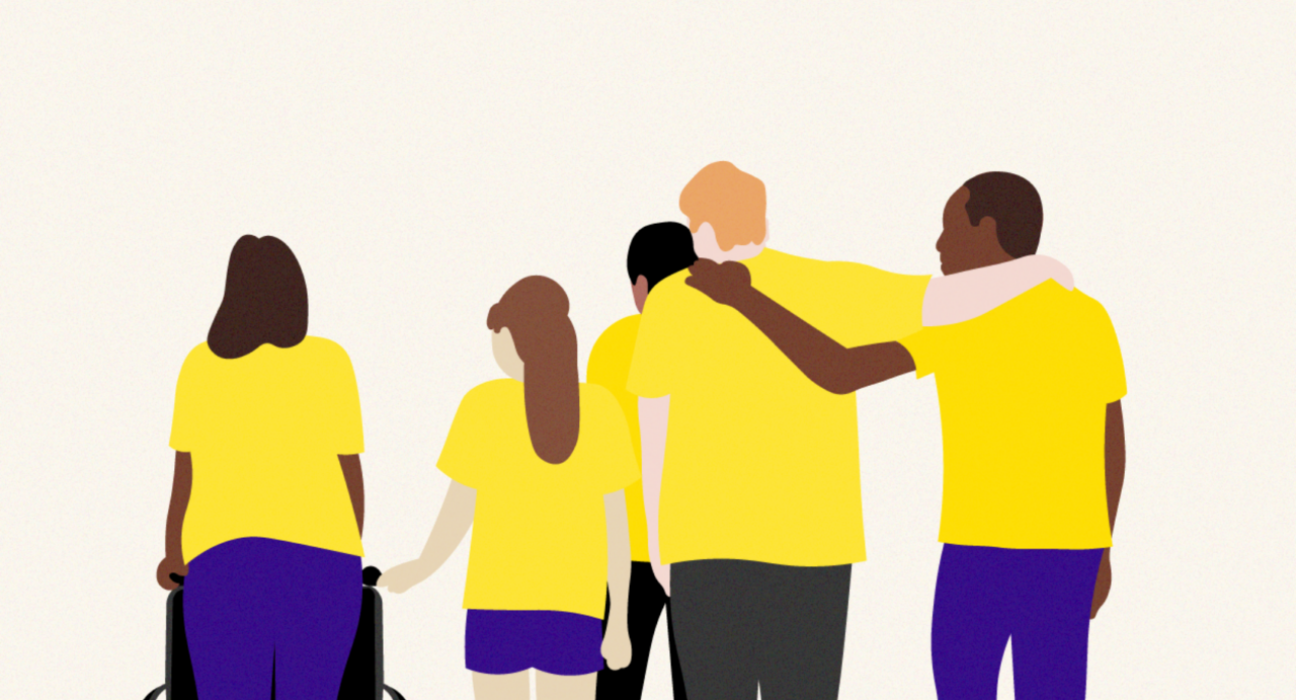 A group of people are supporting one another. They are different ages and from different backgrounds. One is pushing a wheel chair, and another has an arm around another person. It has a supportive feel.