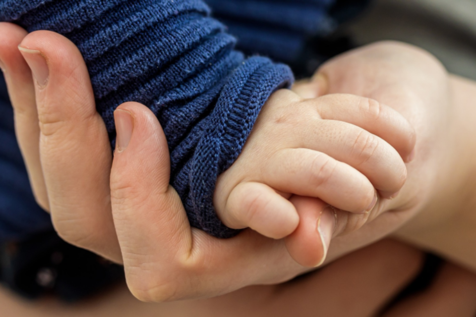 A close up of a baby's hand grasping the parent's hand