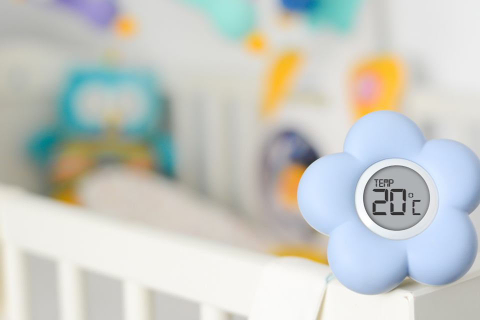 A thermometer, shaped as a flower, sits on a baby's cot.