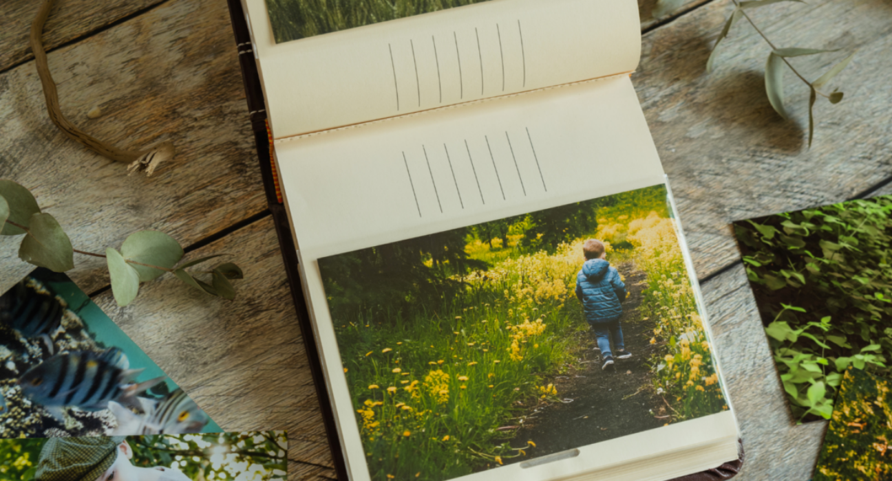 A photo album lays out on a table with a photo of a young child with their back to the camera, walking through a field of flowers.