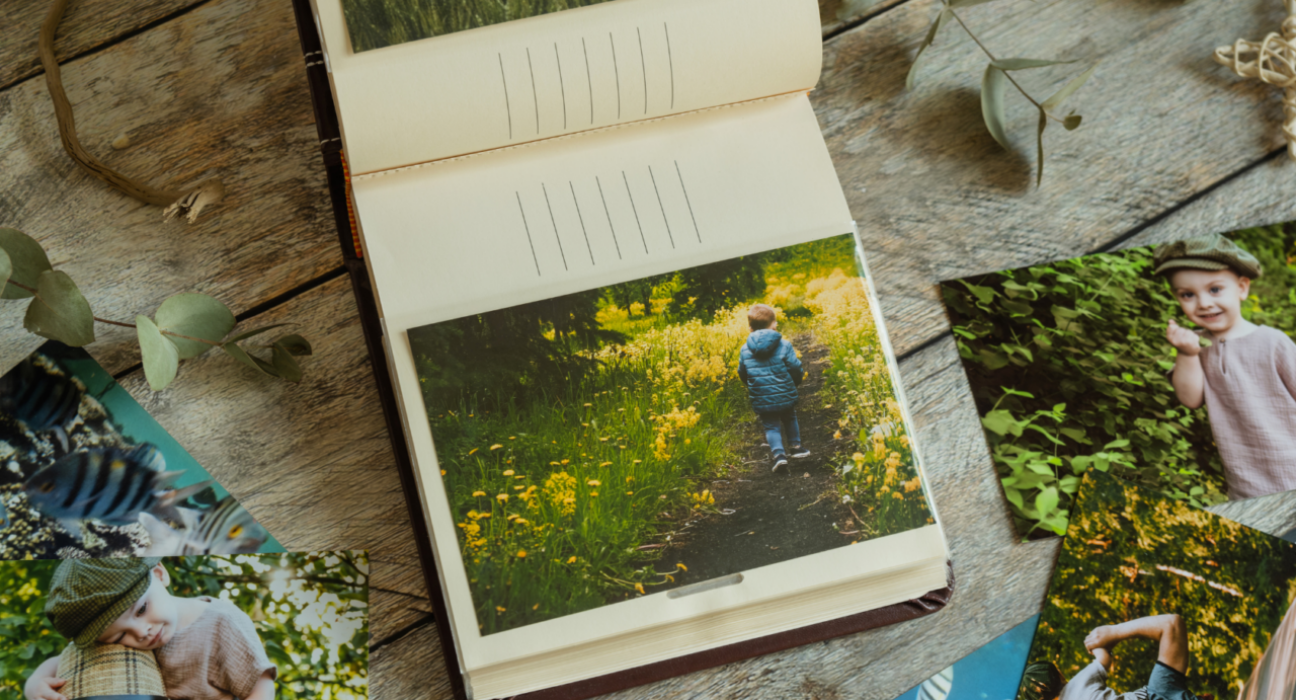 A photo album is open on the page of a little boy walking. He has his back to the camera, walking through forget-me-not flowers.