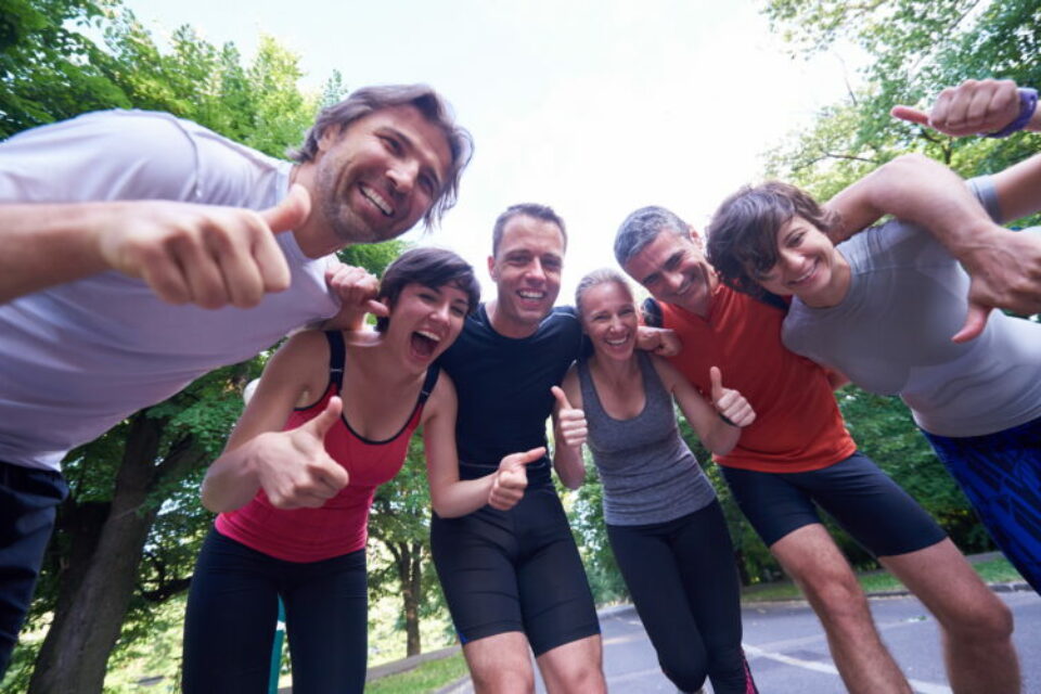 Group of people in active wear smiling at the camera with thumbs up