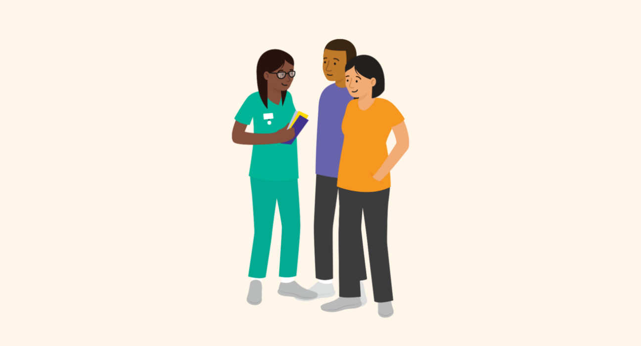 A health professional speaks with a couple. The woman is pregnant. The couple are looking and engaging with the health professional, who is holding booklets in her hand.