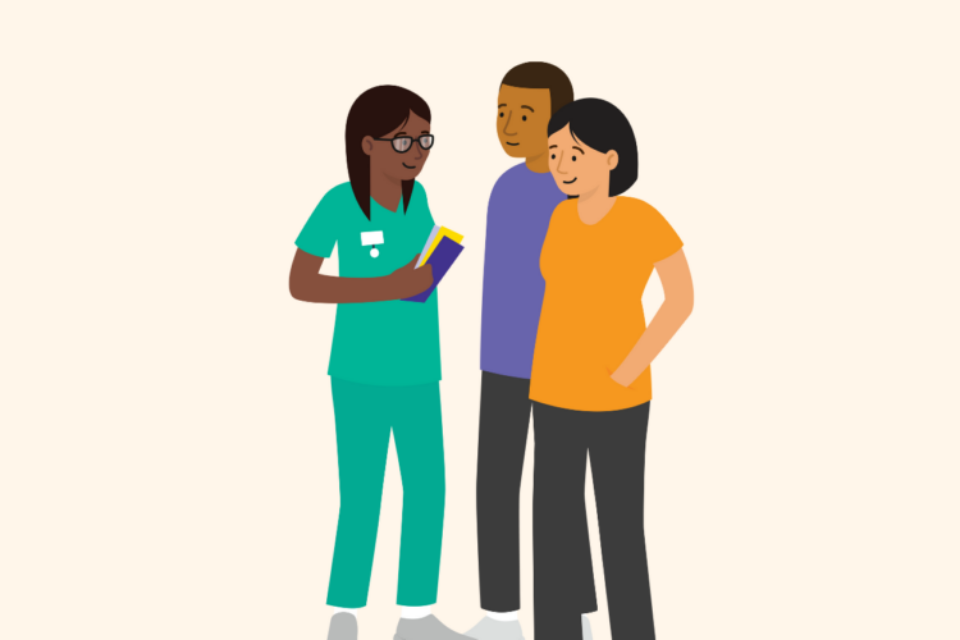 A health professional speaks with a couple. The woman is pregnant. The couple are looking and engaging with the health professional, who is holding booklets in her hand.