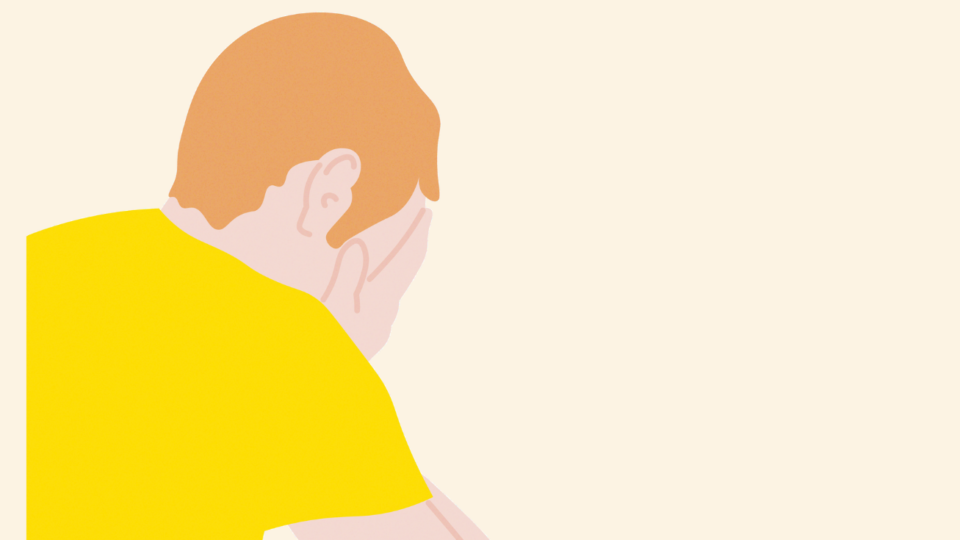 Man in a yellow t-shirt with his head in his hands.