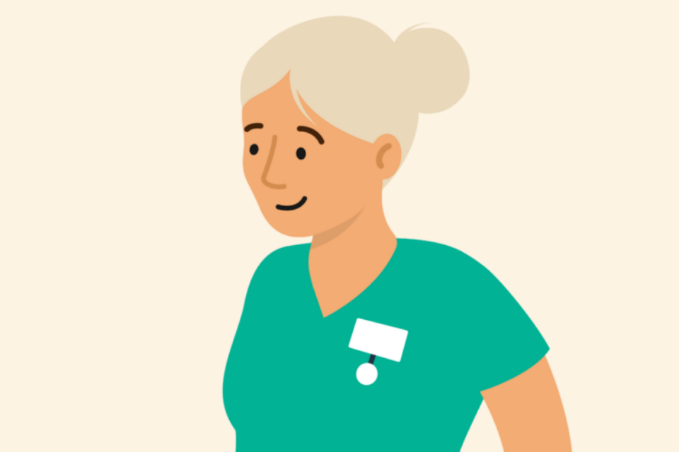 Health professional with grey hair wearing scrubs and smiling.