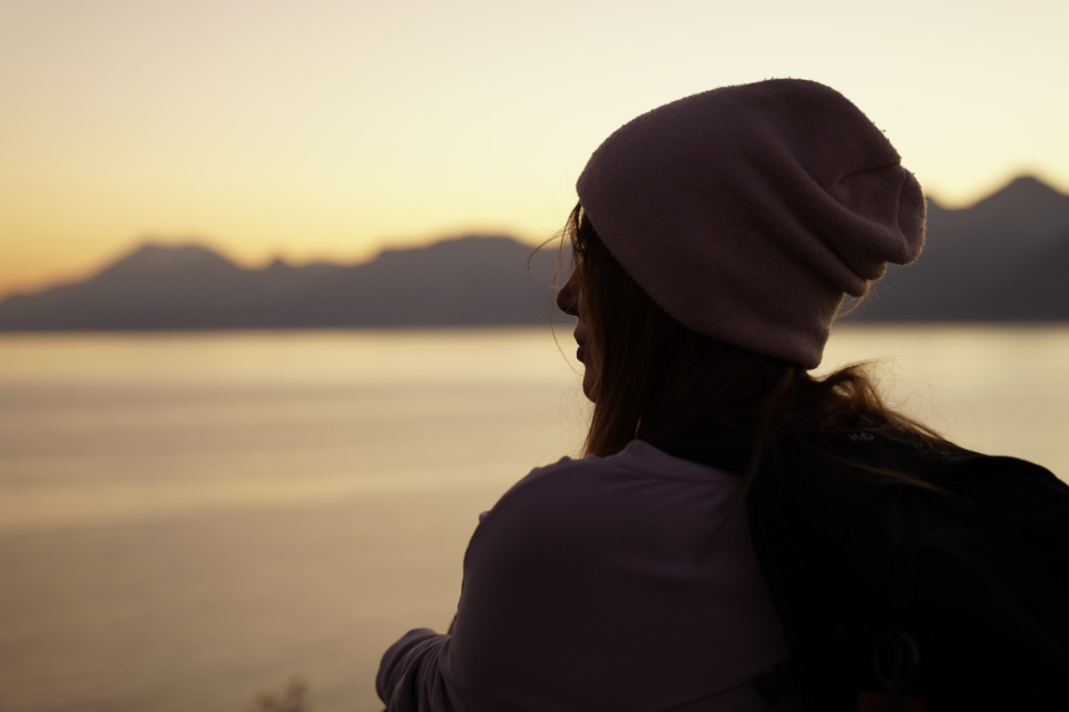 Lady wearing a beanie looking out onto a vast landscape.