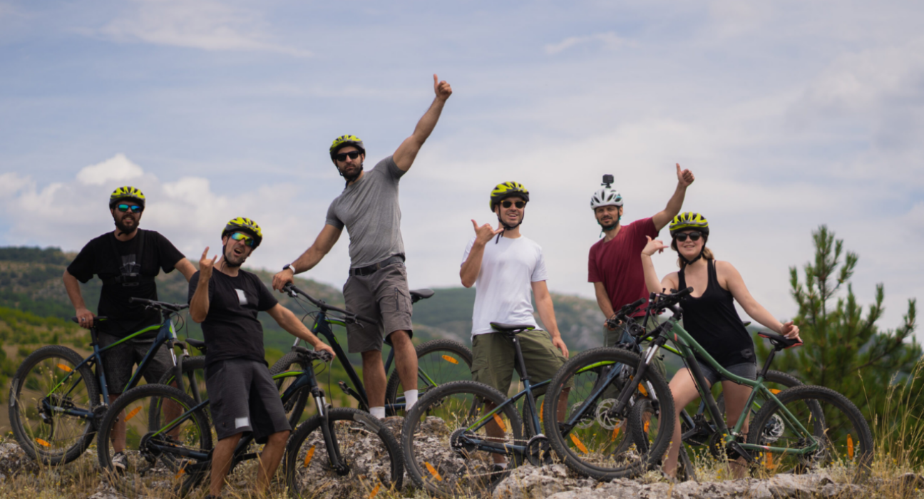 Group of happy friends with bikes are posing on top of the hill