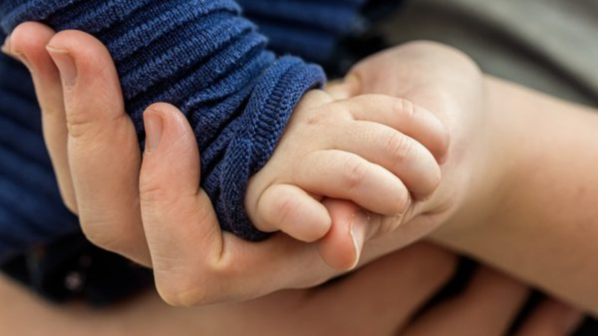 Baby's hand on an adult's hand, close up.