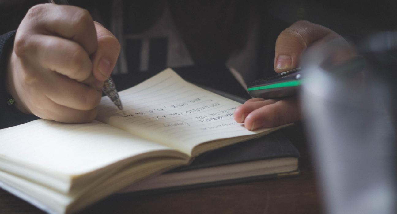Close up of person taking notes in a notebook.