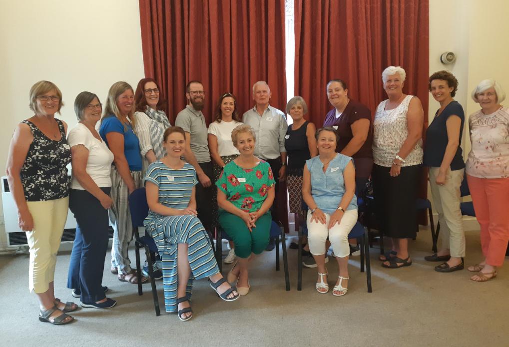 Group of befrienders, some sitting and some standing, all smiling at the camera.