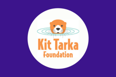 The Kit Tarka logo sits in a circle in the centre of a purple background. The logo reads, Kit Tarka Foundation and there is an illustration of an orange otter with water rings around it's head, as it pops out of the water.
