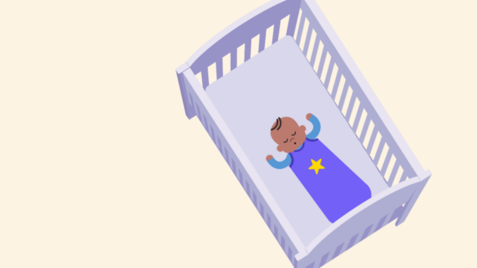 Baby in a sleeping bag sleeping at the foot of a cot.