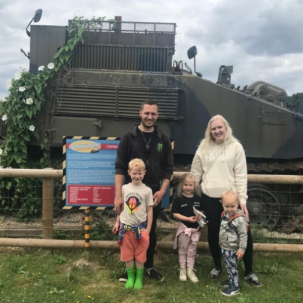 Family standing together smiling in front of a large digger at Diggerland.