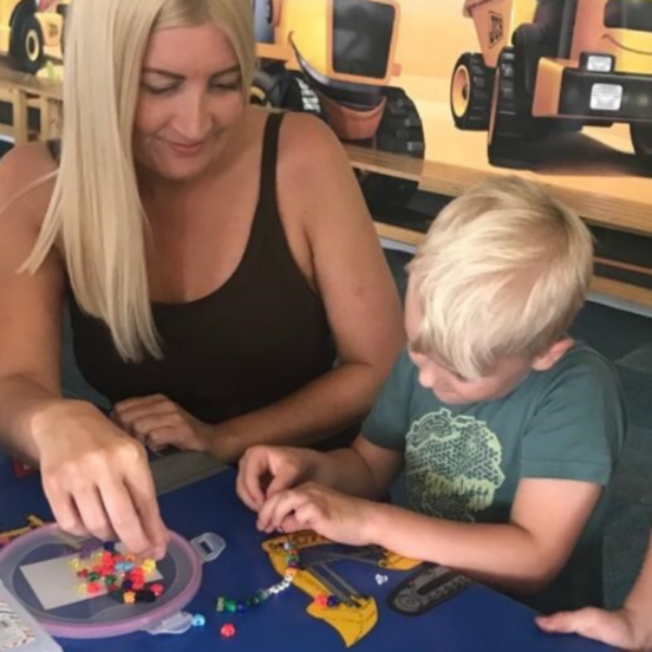 Little boy and lady making bracelets together.