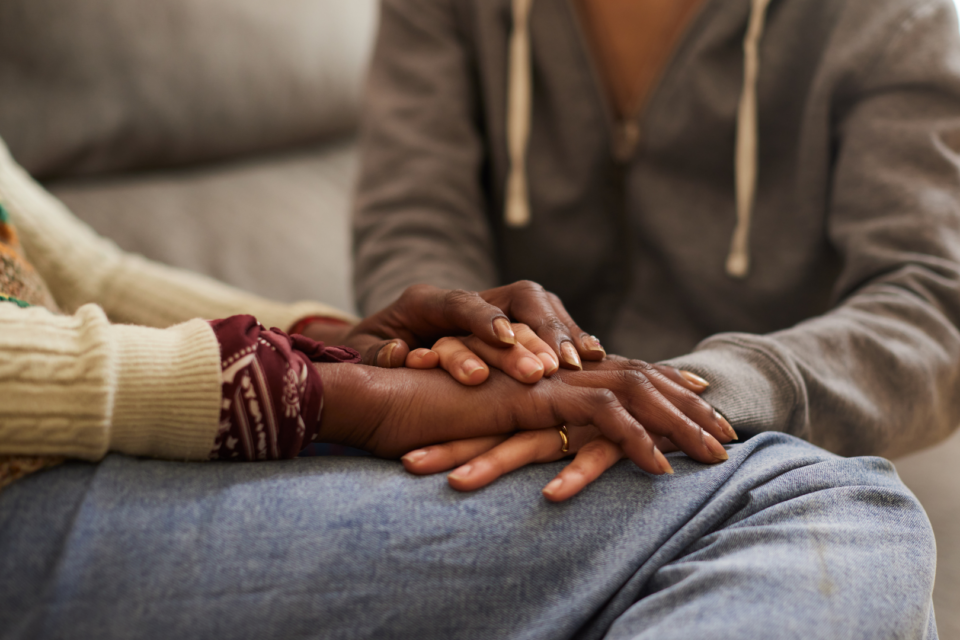 Two people are supporting one another by holding hands. They have dark skin.
