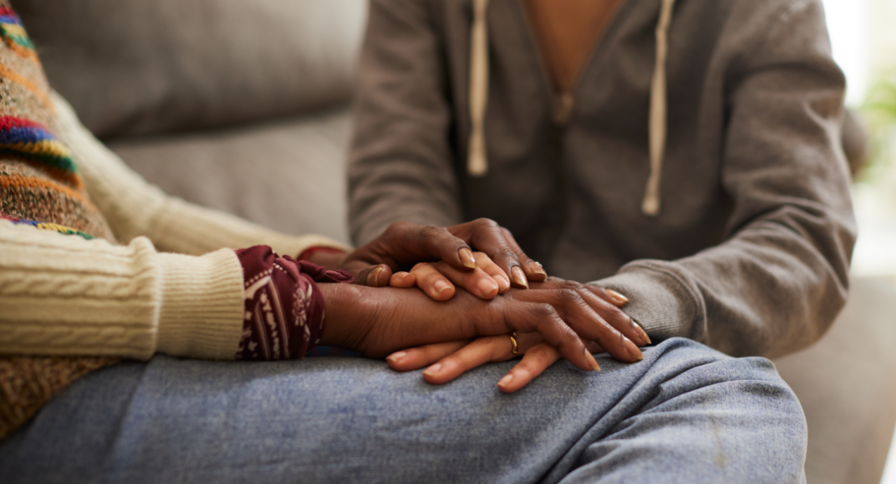 Two people are supporting one another by holding hands. They have dark skin.
