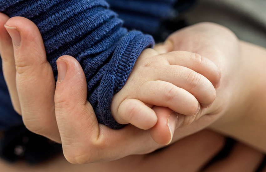 A close up of a baby's hand grasping the parent's hand
