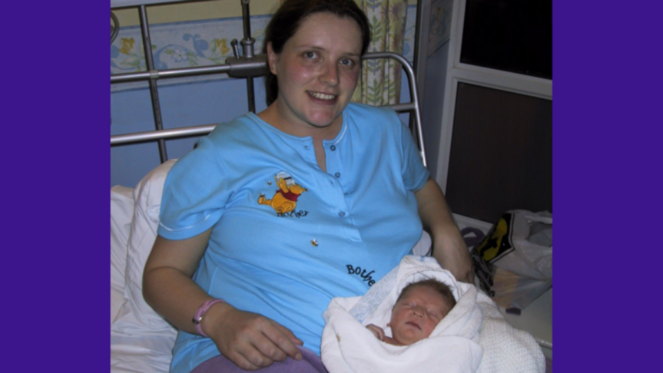 Louise is in hospital after giving birth to Ellis. Ellis is resting in a towel on her lap and she is smiling.