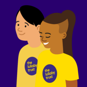 Illustration of two people wearing Lullaby Trust t-shirts. One has medium-dark skin, and the other fair. They are both smiling.