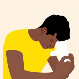 Man holding a teddy bear, resting his head on the bear's head.