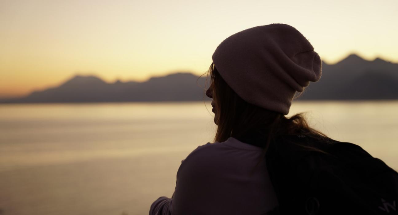 Lady wearing a beanie looking out onto a vast landscape.
