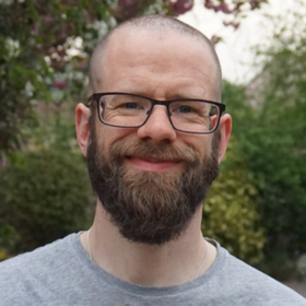 Rob, a befriender, standing outdoors, smiling at camera.