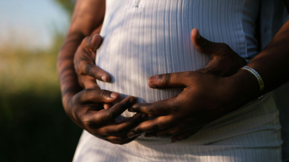 Pregnant tummy with hands resting upon it.
