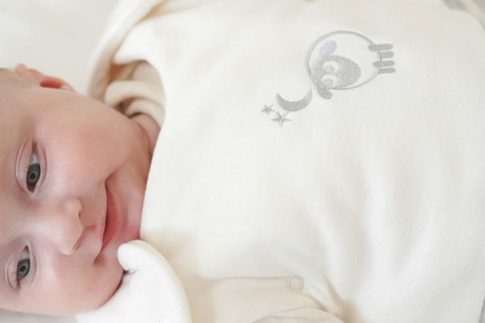 A baby smiling while in a sleeping bag