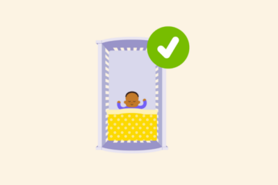 Baby in cot with blanket tucked in.