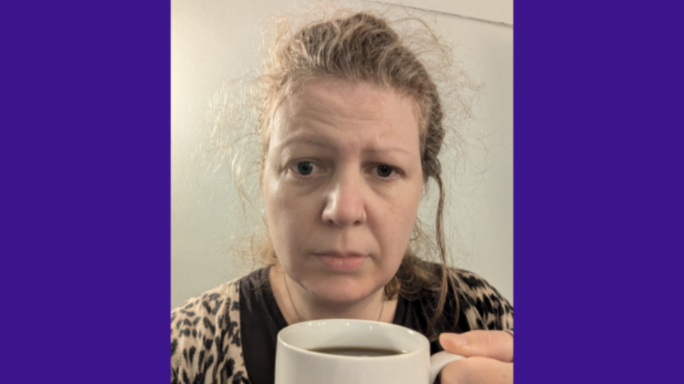 Lucy holding up a cup of coffee, keeping her awake.