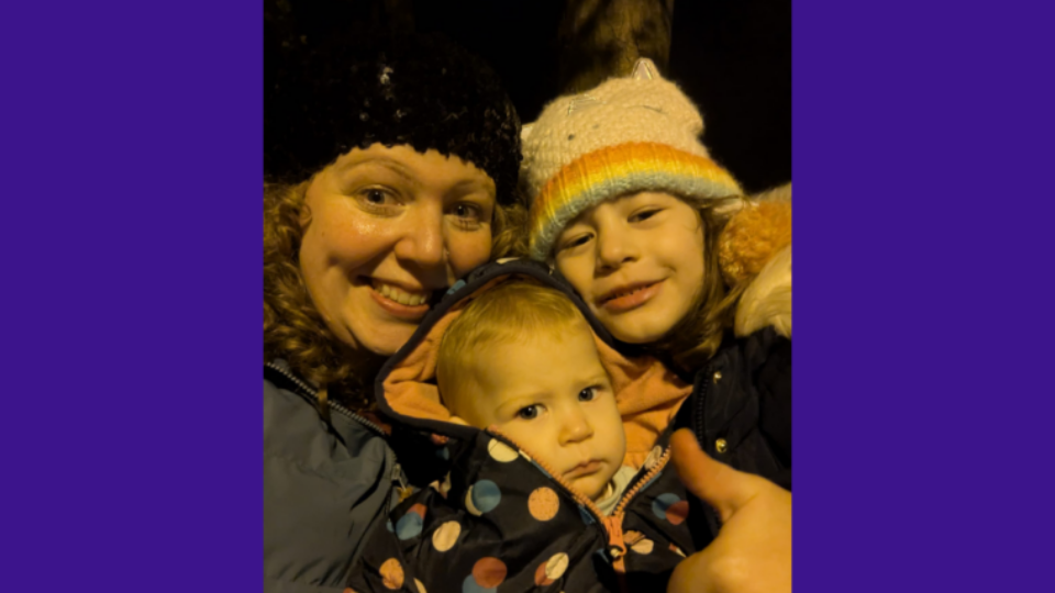 Lucy and her children in coats and wooly hats, smiling at the camera.