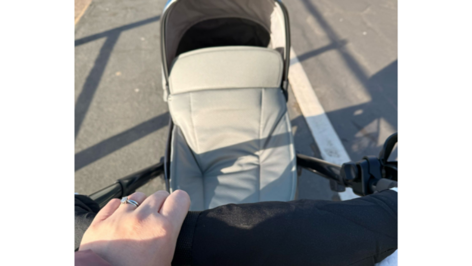 Becky with her hand on the buggy, pushing the buggy along the street on a sunny day.