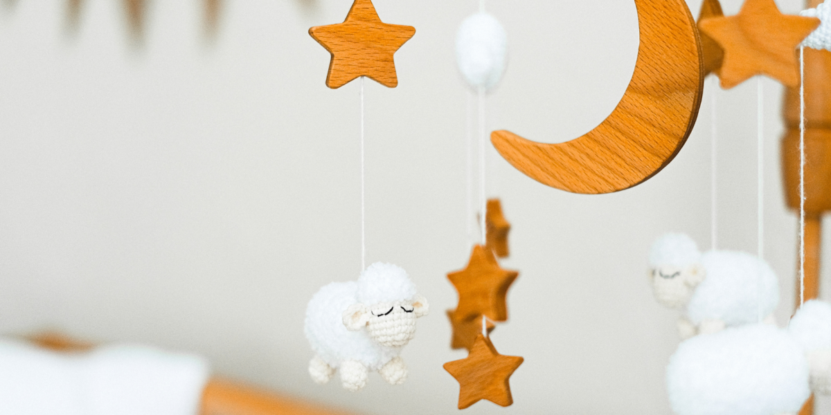 Dangling toys above a babys crib with stars, woolen sheep and moons.
