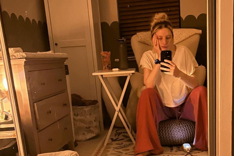 Jess sitting in her child's bedroom at night on a stool, with her chin resting on her hand.
