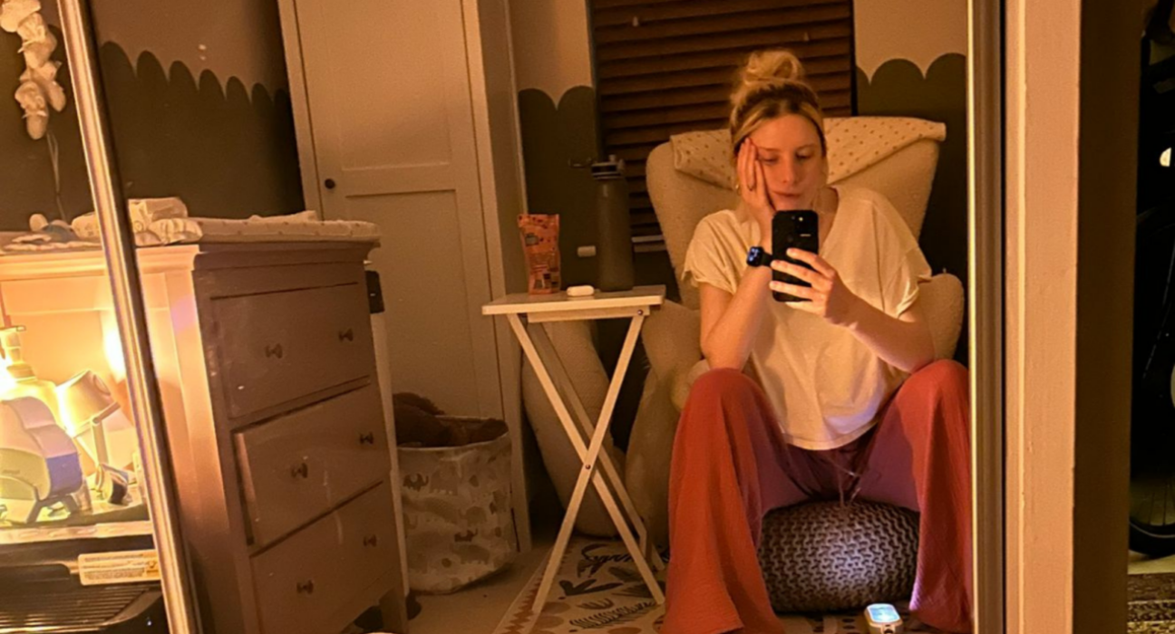 Jess sitting in her child's bedroom at night on a stool, with her chin resting on her hand.