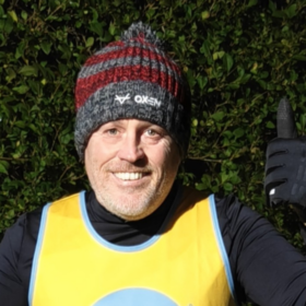 Karl wearing his yellow Lullaby Trust hoodie and a beanie, smiling at the camera.
