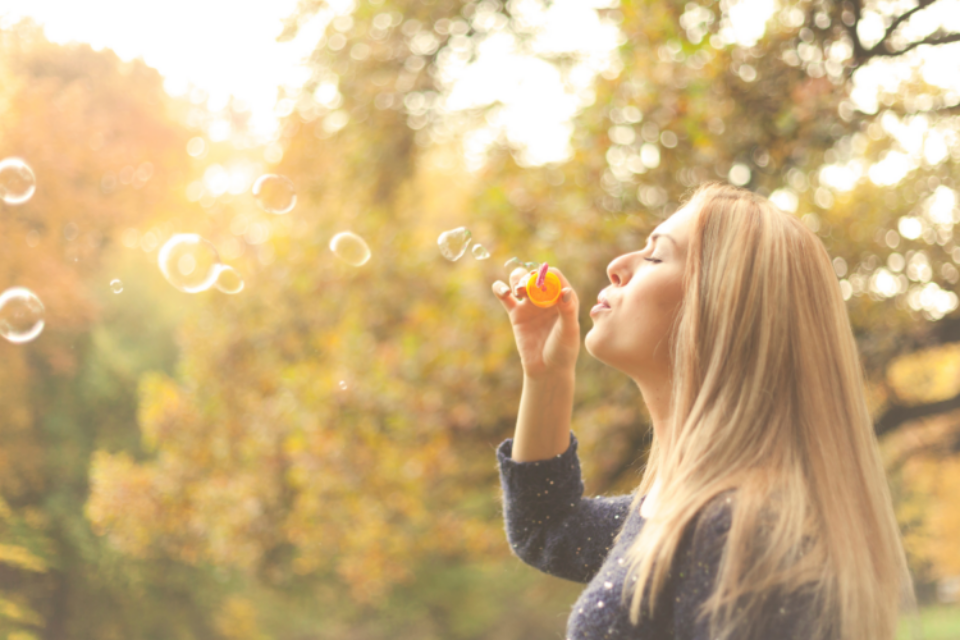 Lady outdoors blowing bubbles.