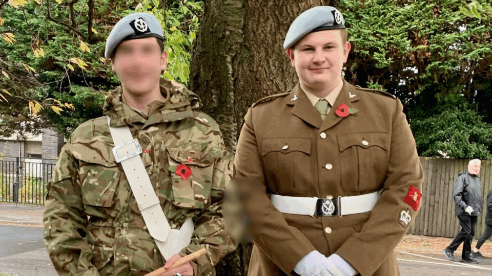 Matt is wearing his full army uniform including a a brown buttoned-up jacket, a white belt, white gloves, and a hat.