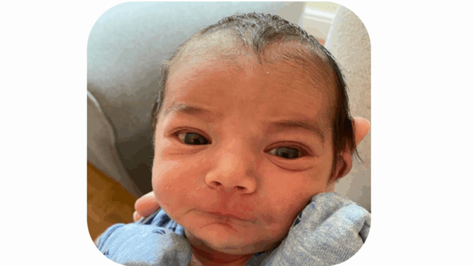 Baby Joshua, a close up of his face. His eyes are open and he has short brown wispy hair.