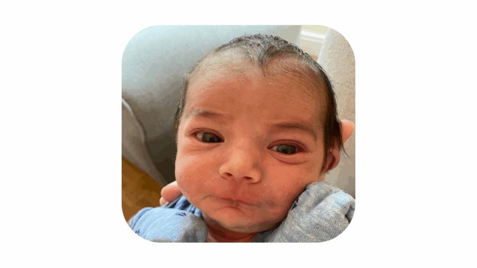 Baby Joshua, a close up of his face. His eyes are open and he has short brown wispy hair.